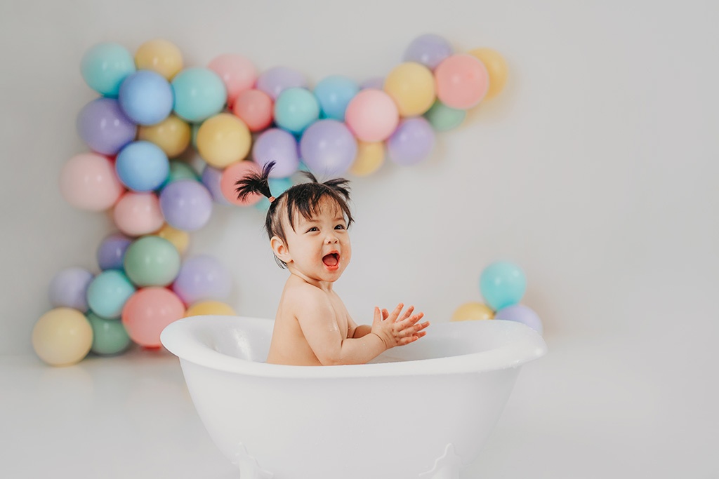 1 year old baby girl in a white porcelain tub after a studio cake smash session.